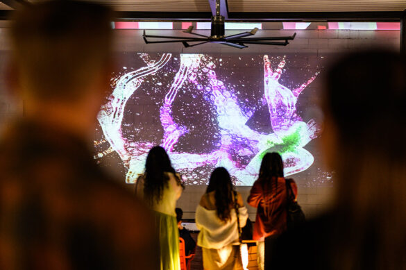 A photograph of a group of people watching a projection of an abstract video work.