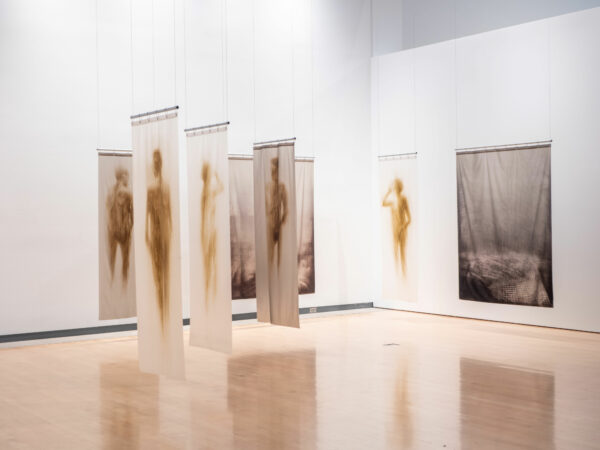 Installation view of shower curtains with the silhouettes of bodies