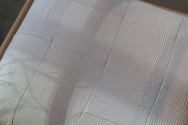 A close up shot of a chair with a seat made of white socks sewn together.