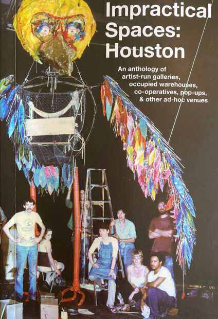 A photograph of the cover of a new book titled "Impractical Spaces: Houston. An Anthology of artist-run galleries, occupied warehouses, co-operatives, pop-ups & other ad-hoc venues." The cover depicts a group of people gathered around the base of a large-scale sculpture of a bird.
