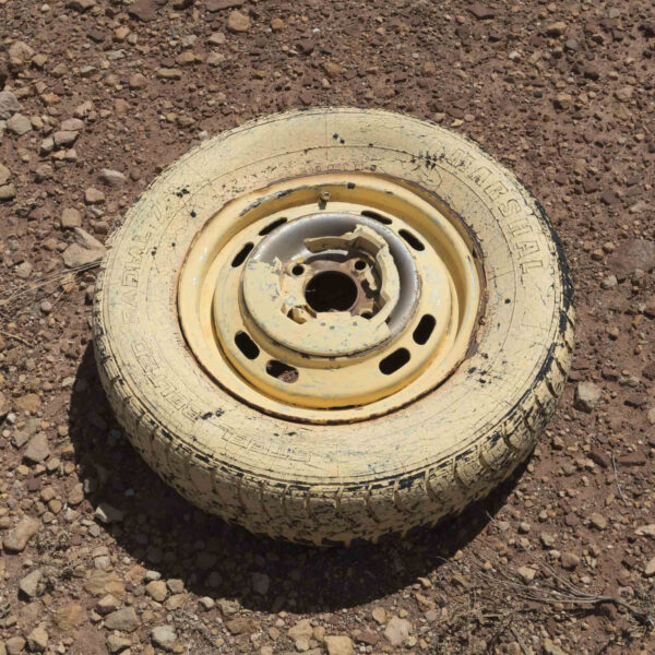 Photo of a dusty, yellow tire on a dirt road