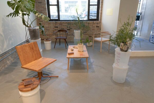 Installation view of fitting with chairs, table, and objects scattered through the room