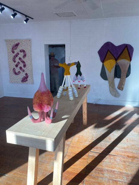 Image of sculptures on a table and works hanging on a wall