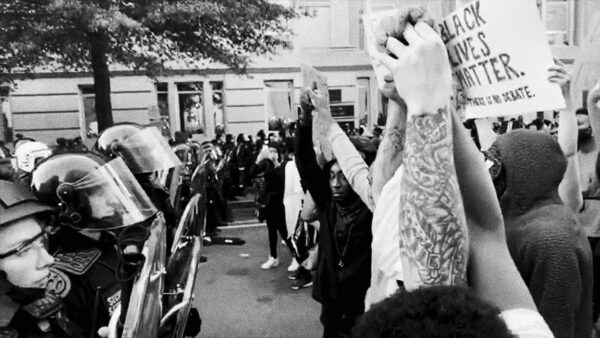 Photo of protestors confronting police with fists in the air