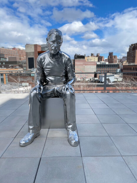 Image of a sculpture of a man sitting on a rooftop