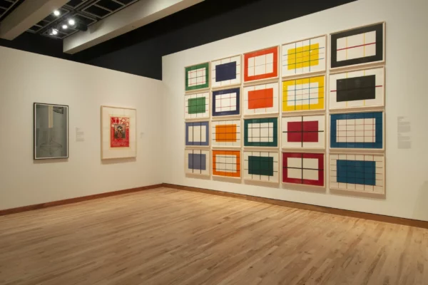An installation photograph showing a 4 by 5 grid of framed colorful gridded artworks. 