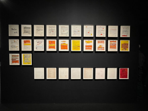 Image of works on paper against a black wall