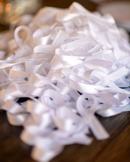 A close up photograph of small white memorial ribbons each held together with a small silver pin.
