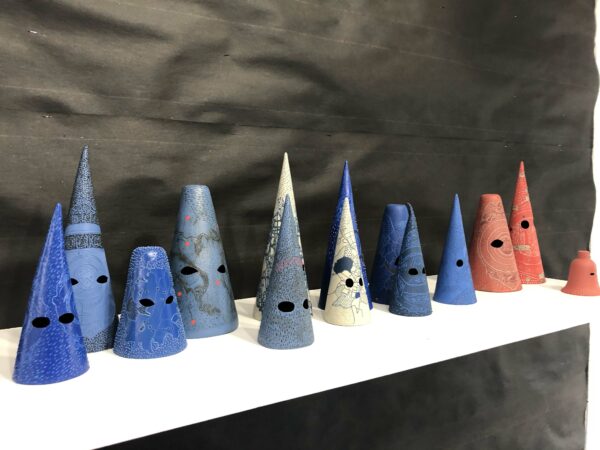 Conical shaped ceramics in blue, white, and red on a shelf