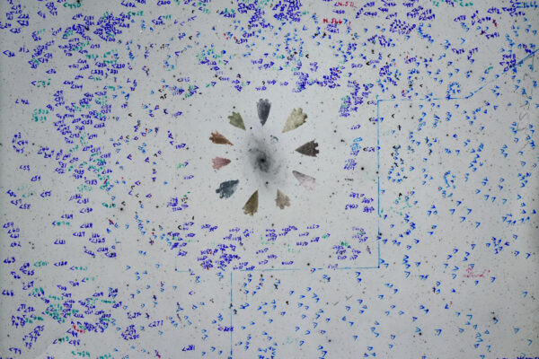 Photo of a work on paper with different shade of blue dots and a center point of arrowheads