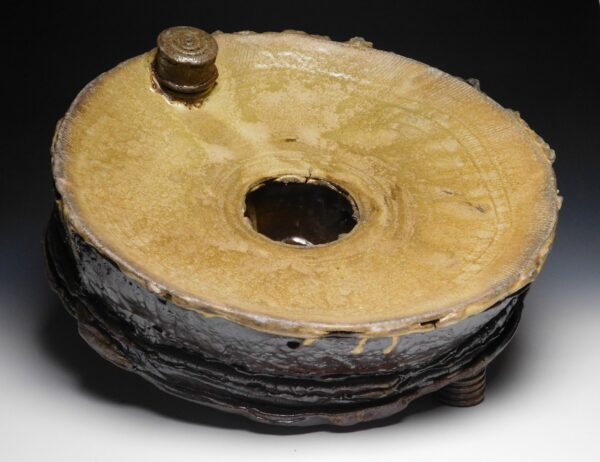 A stoneware piece by Dexter Woods. The work is a short cylinder with a light brown top and dark brown base.