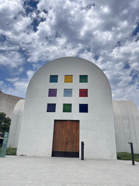 A photograph of the exterior of Ellsworth Kelly's "Austin." The image shows a large wooden door with a 3 x 3 grid of colored glass squares above it.