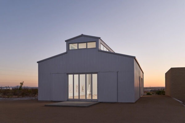 A color photograph of the new gallery Hetzler Marfa set in open landscape with the sun rising behind it.