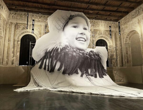 Installation of a large scale work on paper of a smiling child