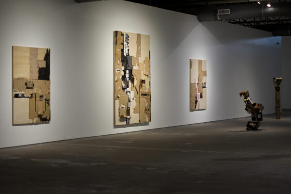 Large scale two dimensional works of collaged cardboard on a white wall