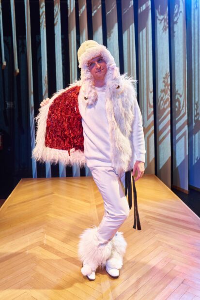 Photo of a man dressed in a white costume wearing an elaborate fluffy hat