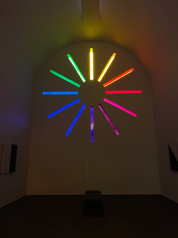 A photograph of the interior of Ellsworth Kelly's "Austin" showing a stained-glass window made from square-shaped colored glass pieces.