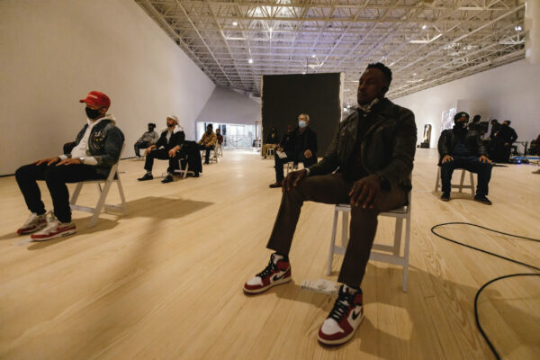 Photo of men sitting in a workshop in a gallery space