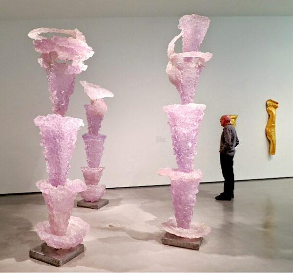 Installation view of three stacked pink totem-like sculptures in a gallery space