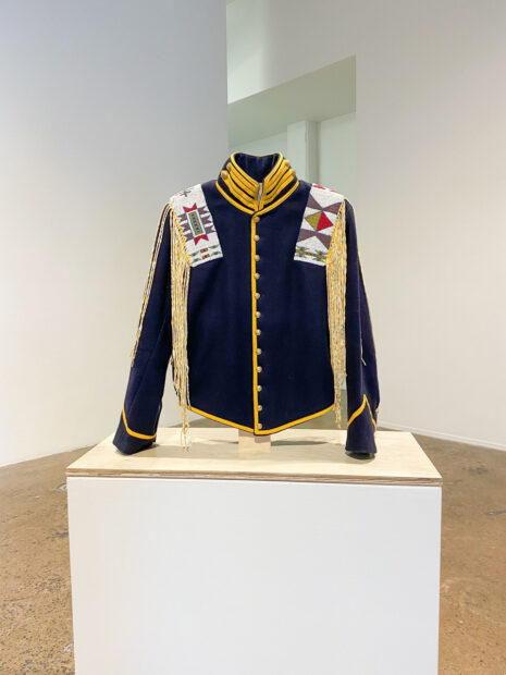 Image of a blue military jacket hanging upright on a pedestal