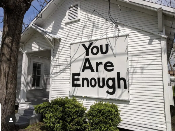Photo of the words "You are Enough" painted on the side of one of the Project Row Houses