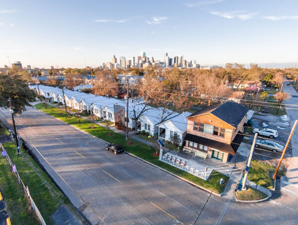 A photograph of an aerial view of Project Row Houses in 2015. The image shows a neighborhood block with over a dozen small white row houses. 