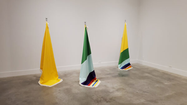 Three colorful flags hang from the ceiling and are draped on the ground.