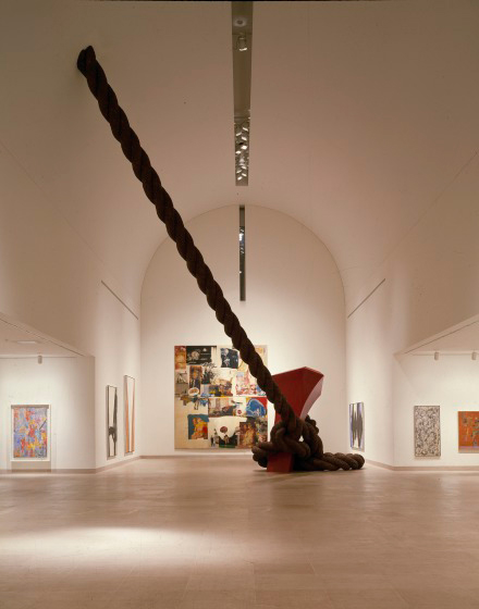 A photograph of the interior of the Dallas Museum of Art showing a larger than life size stake and rope coming out of the museum's floor.