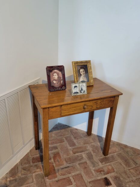 Photo of a small wood end table with antique family photos on top