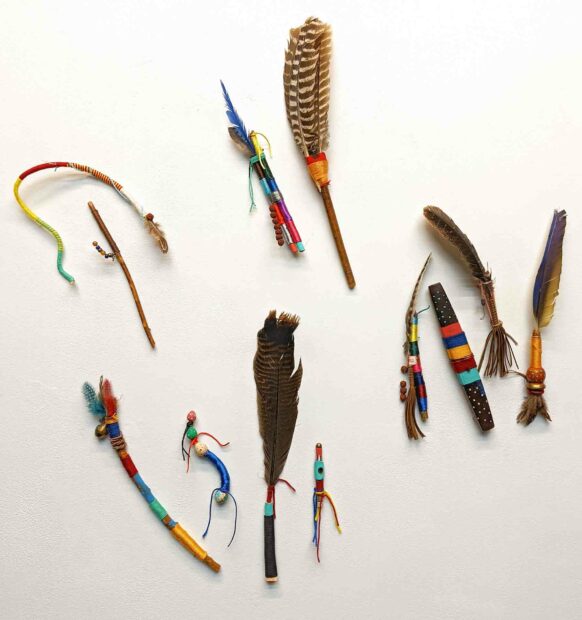 An installation by Dennis Gonzalez featuring feathers, sticks and other natural objects adorned with colorful thread.