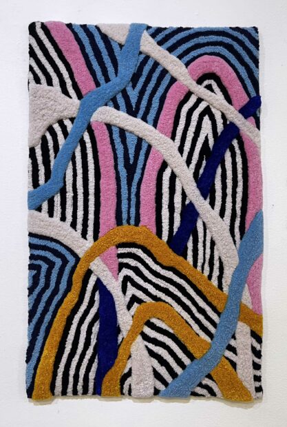 Photo of a vertically oriented tufted rug with white, orange, pink, black and blue colors