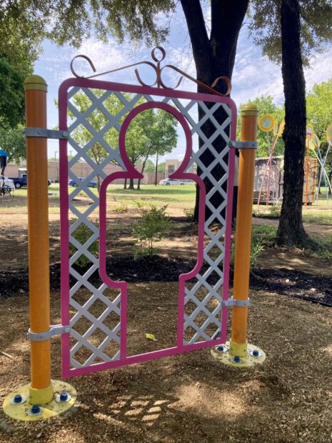 colorful steel sculpture of an oversized fence door with a stylized human frame cut out