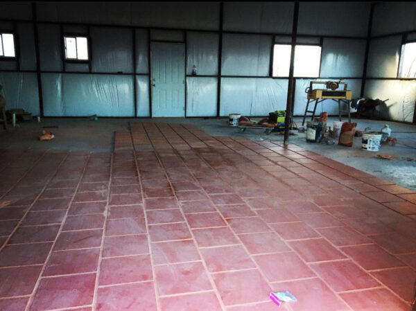 A photograph of the interior of a studio space that artist Ramon G. Deanda is building. The space is still in progress. The walls have not been completed and the floor is only partially outfitted with tiles.
