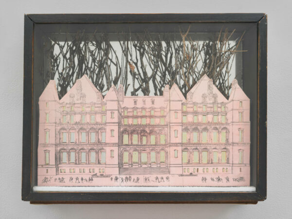 A shadowbox artwork featuring a collage of a large, pink house. There are twigs, representing trees, coming from behind the house.