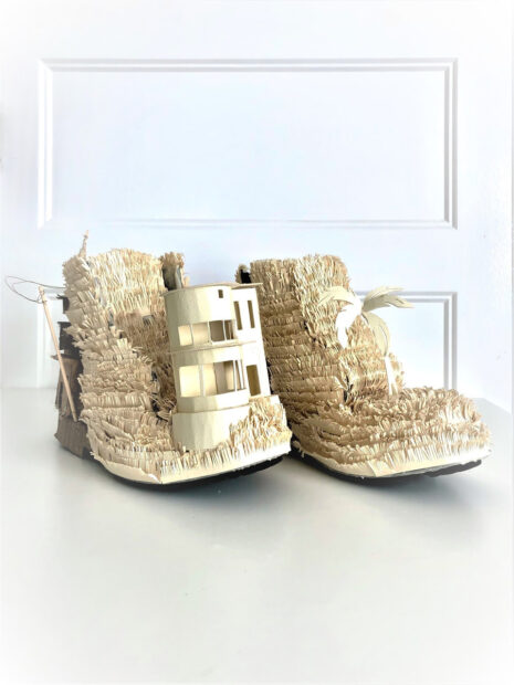 A photograph of a sculpture work by Juan Escobedo. The piece which is made to resemble construction boots is created from cardboard and paper. 