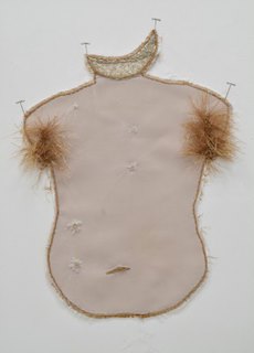 A mixed media work by Krista Chalkley of a human torso. The torso is a pale pink color and has reddish-orange fibers protruding from the armpit area.