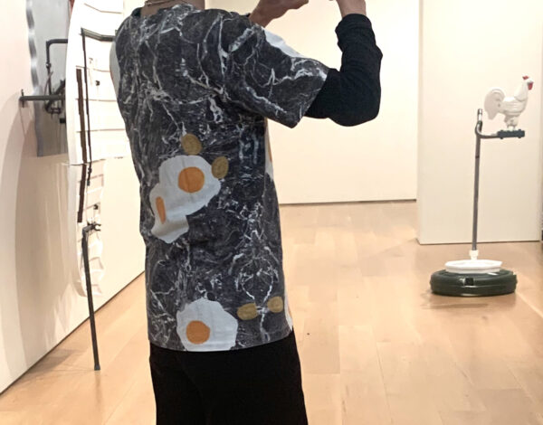 The artist wearing a gray and white tshirt with a sunny side up egg in the pattern