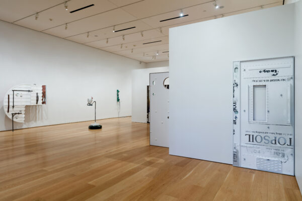 Installation view of large, monochromatic sculptures leaning against a wall and freestanding in space