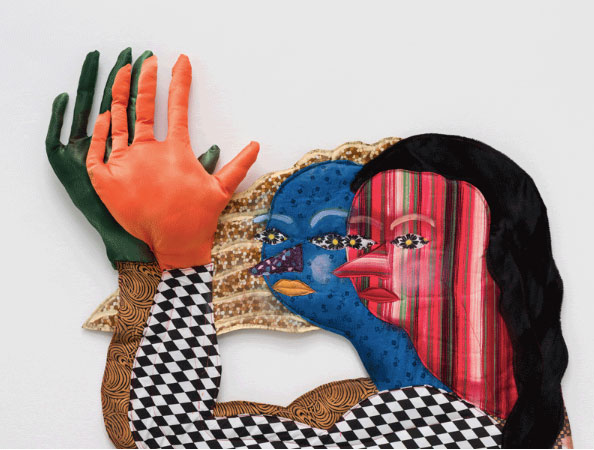 A sculptural work by Maria A. Guzmán Capron of two abstracted figures with long hair. Each figure is made using various patterns of fabric.