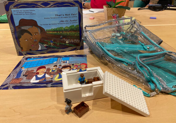 A photograph of an educational activity designed for the National Museum of the American Latino. A clear backpack has a book and hands-on building activity laid next to it.