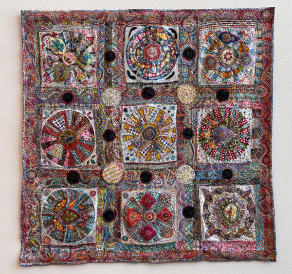 A large intricate quilt by Pamela Studstill that features nine large pinwheel shapes. 