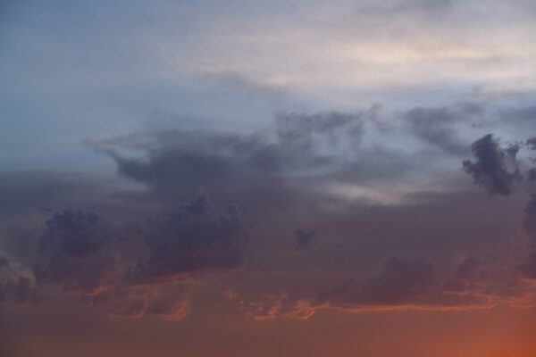 Azules, morados y naranjas se degradan en esta fotografía de un cielo medio nublado.