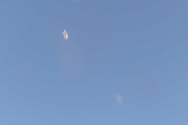 A surveillance blimp flying in a big blue sky