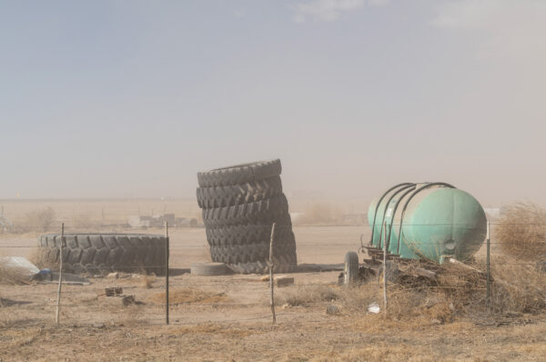 green propane tank and stacks of tires in a dry desert landscape