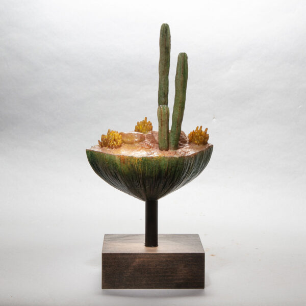 A sculpture of a desert landscape, featuring cacti, rocks, and brush.