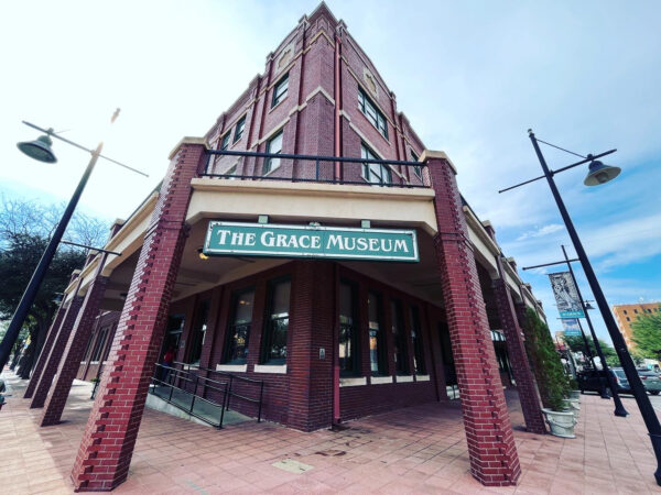 A photograph of The Grace Museum in Abilene, Texas. The museum is a large, brick building.