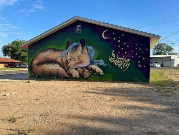 A mural of a mother coyote and her pup resting below a night sky that has 21 stars, one for each victim of the Uvalde shooting.
