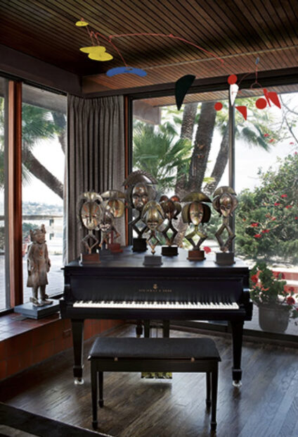 Photo of a piano in a room with various african sculptures on top