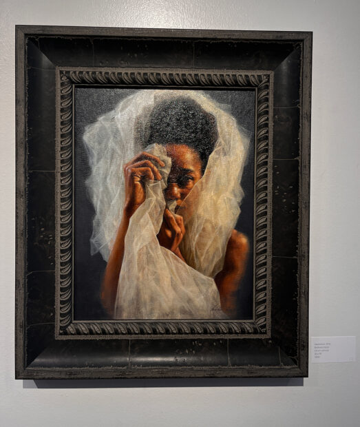 A portrait of a Black woman partially covered by a thin white tulle-like fabric.