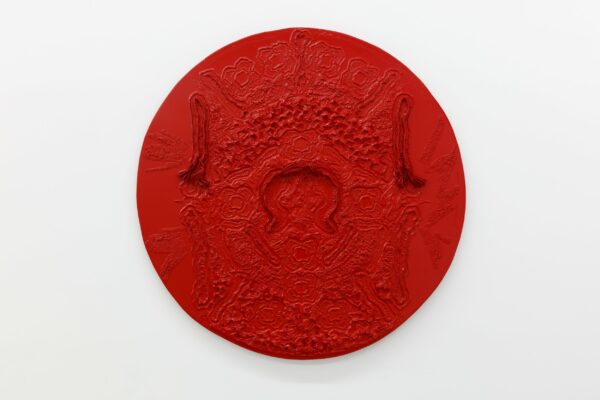 A large circular work by David Jeremiah. The heavily textured piece is painted a solid red.